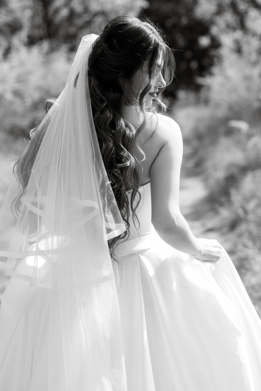 a young girl bride in a white dress is spinning on a path