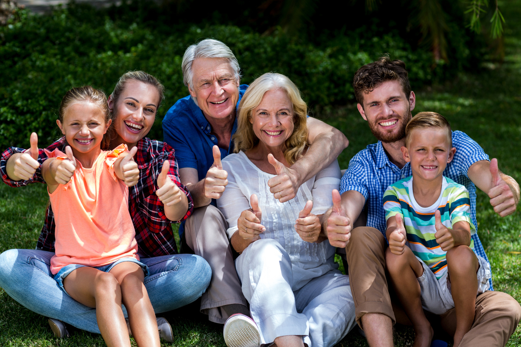 Potrait of family gesturing thumbs up at yard